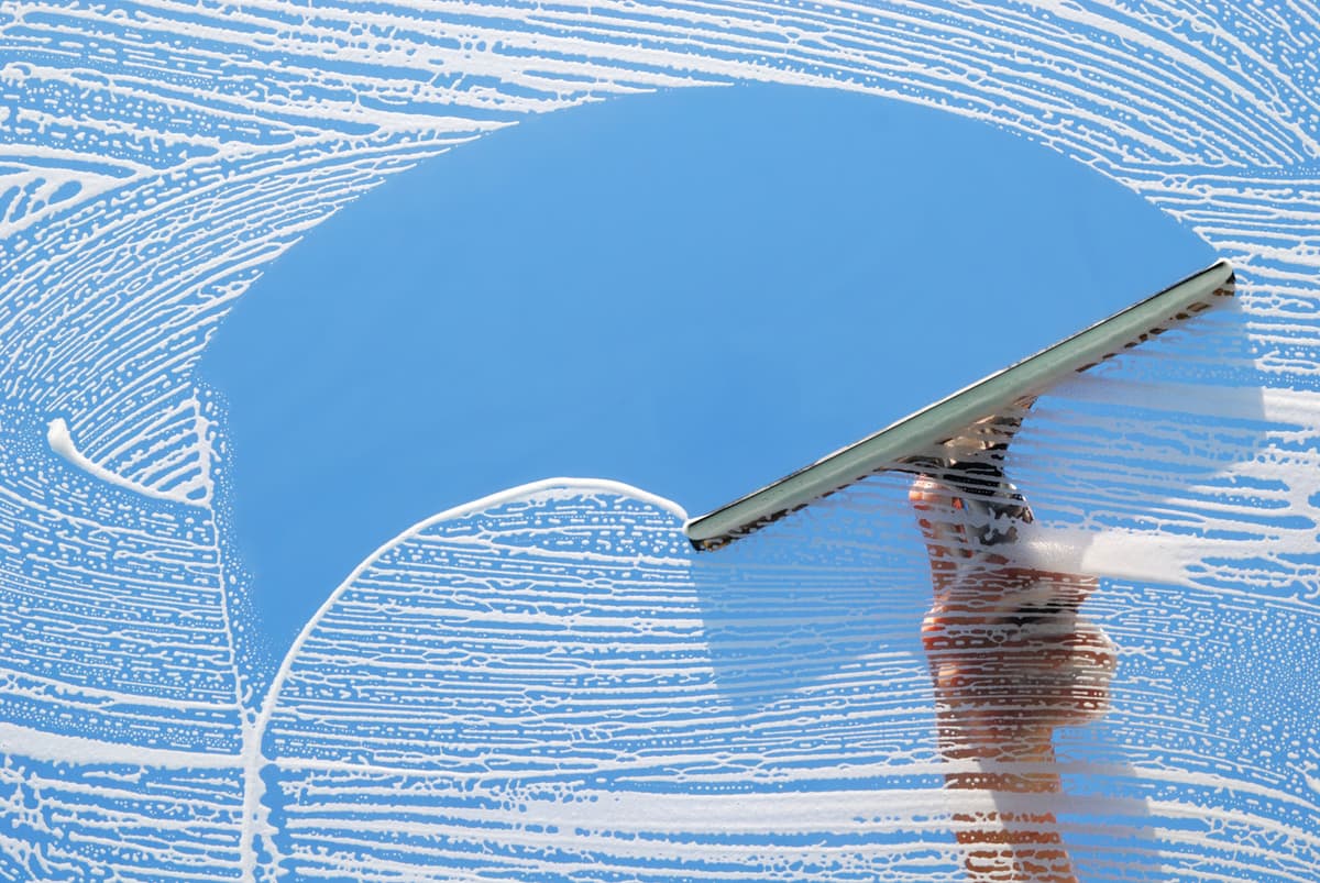 Squeegee clearing soap suds from a glass window